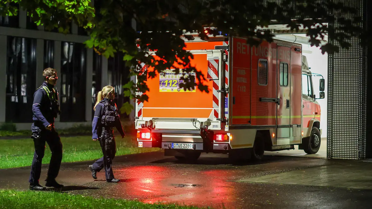 06.05.2026, Nordrhein-Westfalen, Dsseldorf: Polizisten laufen an einem ankommenden Rettungswagen vorbei, der eine deutsche Patientin in das Infektionszentrum der Uniklinik Düsseldorf bringt. Foto: Christoph Reichwein/dpa +++ dpa-Bildfunk +++