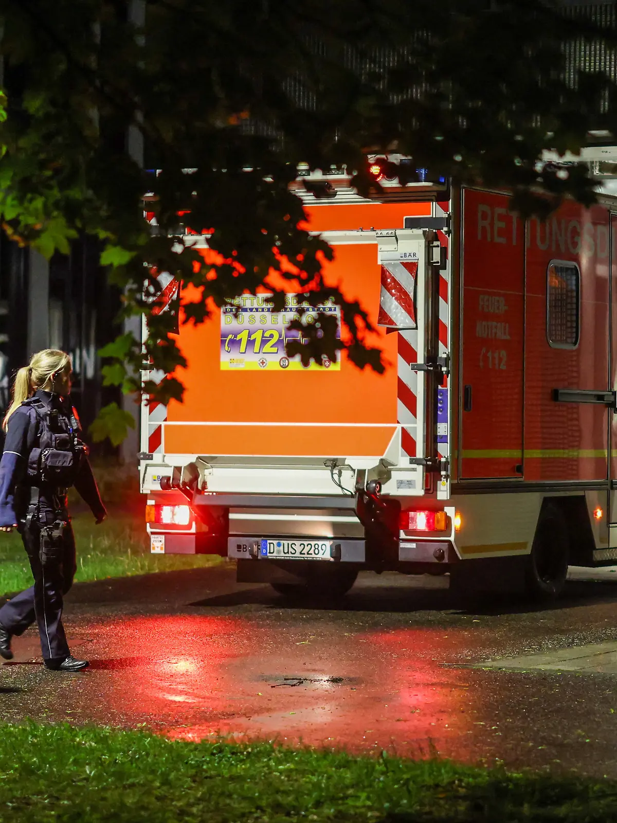 06.05.2026, Nordrhein-Westfalen, Dsseldorf: Polizisten laufen an einem ankommenden Rettungswagen vorbei, der eine deutsche Patientin in das Infektionszentrum der Uniklinik Düsseldorf bringt. Foto: Christoph Reichwein/dpa +++ dpa-Bildfunk +++