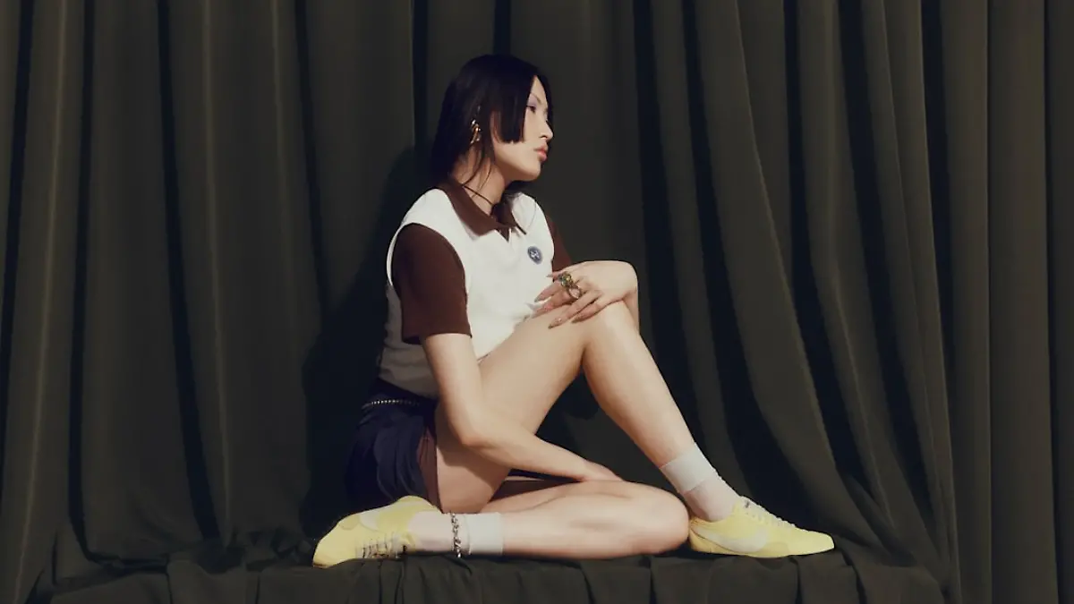 Model mit gelben Nike Moon Sneakern vor dunklem Hintergrund.