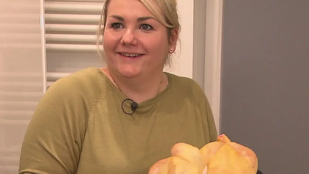 Diana hält eine Auflaufform mit einem dicken Maishähnchen.
