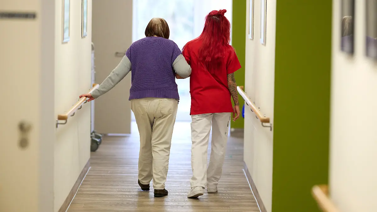 Eine Pflegekraft begleitet im DRK-Pflegezentrum Solferino eine Seniorin durch den Flur. (zu dpa: «Klassische Geschlechterrollen prägen Bayerns Arbeitsmarkt») +++ dpa-Bildfunk +++