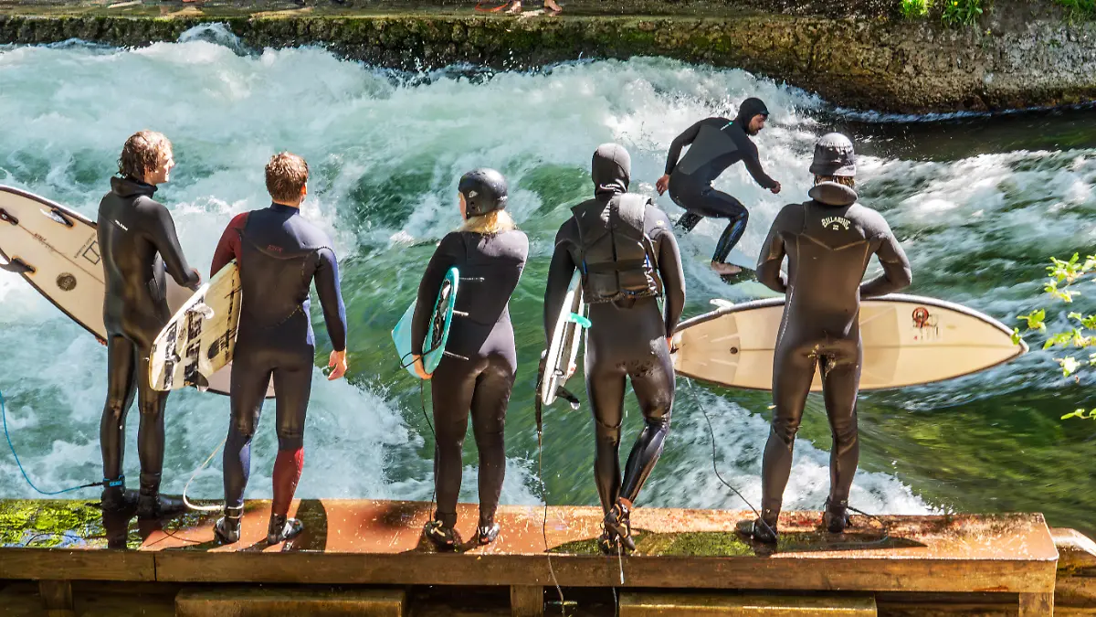 Deutschland, München, 2. Mai 2026, die berühmte Surfwelle läuft wieder! Surfer auf der Eisbachwelle am Samstagmittag, viele Münchner und Touristen säumen das Bachufer, alle freuen sich über die Rückkehr der Welle, die Surfwelle ist seit ein paar Tagen wie durch ein Wunder wieder da, Spekulation: durch höheren Wasserstand und eine bessere Strömung hat sich die perfekte Welle wohl von selbst wieder stabilisiert, es sind keine illegalen Einbauten bekannt, es gilt jedoch weiter das Surfverbot der Stadt, schönster Frühlingswetter mit Temperaturen um die 23, 24 Grad, River Surfing, Frühling, Bayern,