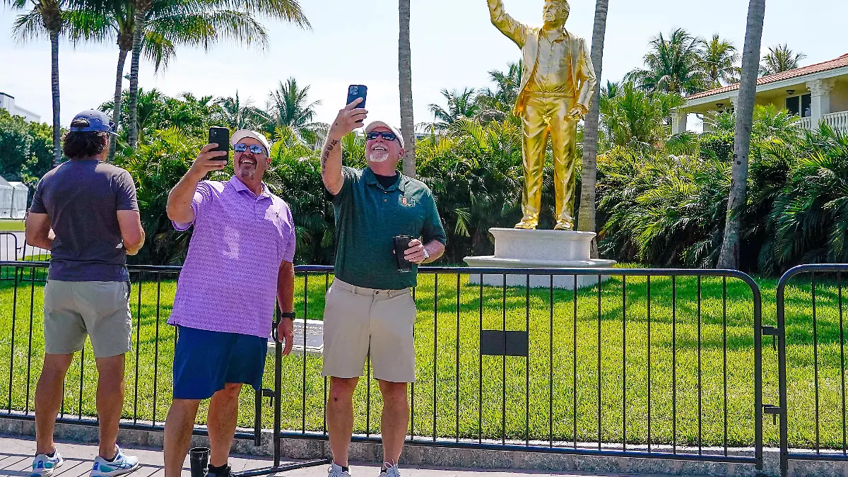 Apr 30, 2026; Miami, Florida, USA; Fans pose for a photo in front of a statue of President Donald Trump during the first round of the Cadillac Championship golf tournament. Mandatory Credit: Jeff Romance-Imagn Images