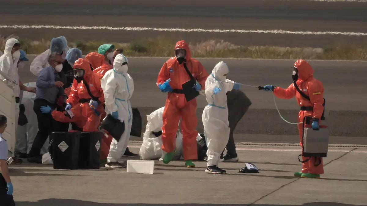 Spanische Regierungsbeamte besprühen auf dem Flughafen von Teneriffa Passagiere mit Desinfektionsmittel, bevor diese ein Flugzeug besteigen. Zuvor waren sie vom Hantavirus befallenen Kreuzfahrtschiff MV Hondius gebracht worden. Das von einem Ausbruch des Hantavirus betroffene Kreuzfahrtschiff MV Hondius liegt im Hafen von Granadilla im Süden der spanischen Urlaubsinsel. Die Evakuierung des Schiffs hat begonnen. +++ dpa-Bildfunk +++