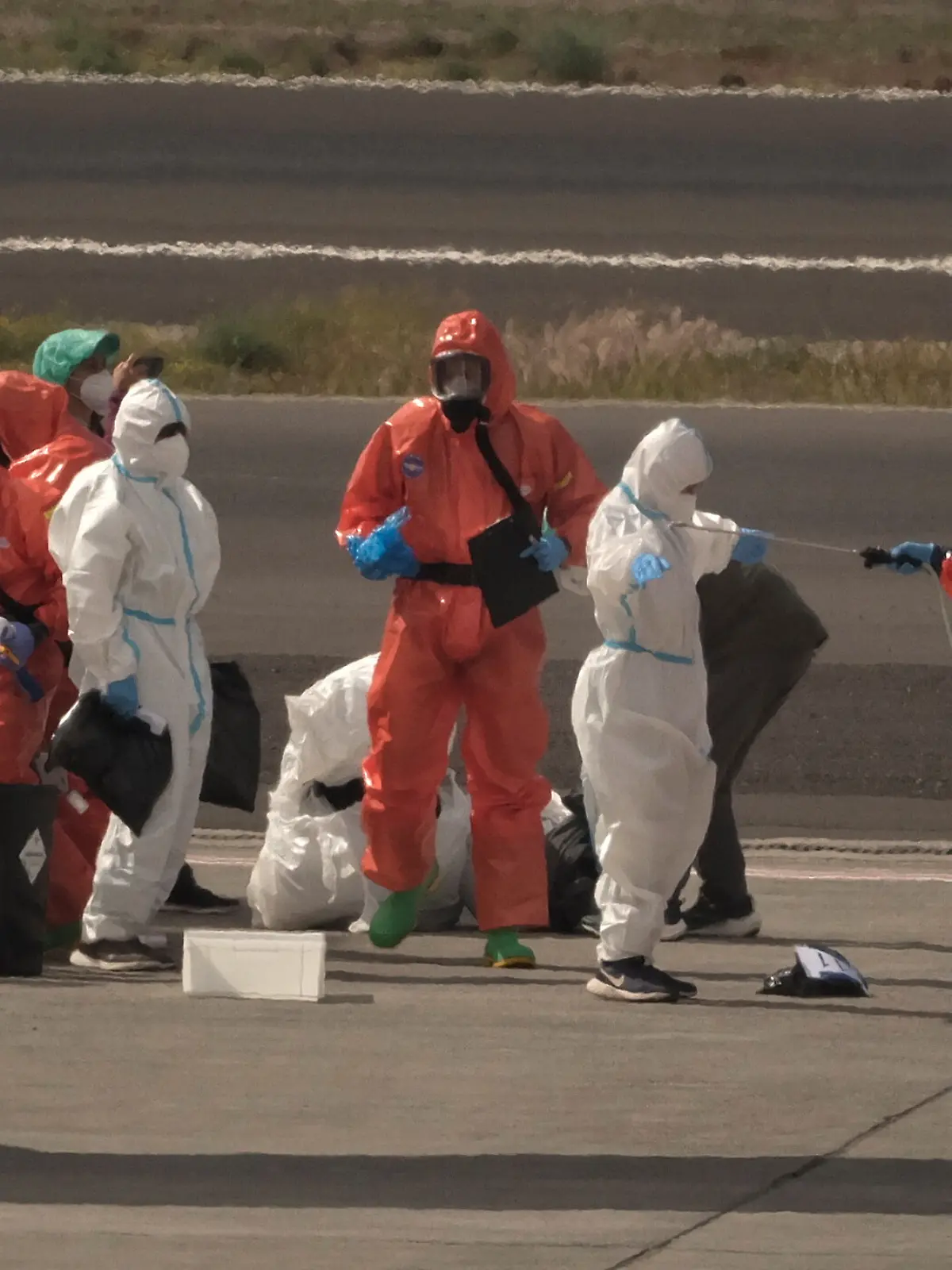 Spanische Regierungsbeamte besprühen auf dem Flughafen von Teneriffa Passagiere mit Desinfektionsmittel, bevor diese ein Flugzeug besteigen. Zuvor waren sie vom Hantavirus befallenen Kreuzfahrtschiff MV Hondius gebracht worden. Das von einem Ausbruch des Hantavirus betroffene Kreuzfahrtschiff MV Hondius liegt im Hafen von Granadilla im Süden der spanischen Urlaubsinsel. Die Evakuierung des Schiffs hat begonnen. +++ dpa-Bildfunk +++