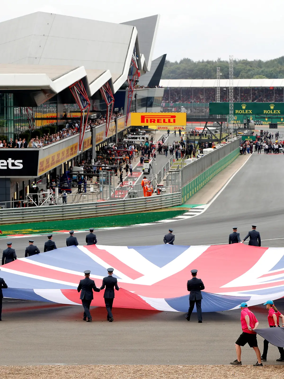 FILE PHOTO: Formula One F1 - British Grand Prix - Silverstone Circuit, Silverstone, Britain - July 14, 2019   General view of a Union Jack flag being carried out on to the track by service personnel before the race   REUTERS/John Sibley/File Photo