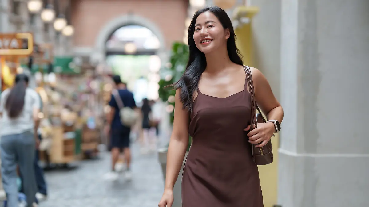 Frau in braunem Satinkleid geht shoppen.