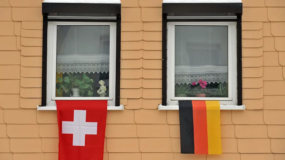 Eine deutsche und eine Schweizer Flagge hängen am Dienstag (02.02.2010) in Klingenthal (Sachsen) am Fenster eines Hauses. Für den Skisprung-Weltcup haben die Einwohner des Ortes die Häuser geschmückt. Der Kauf gestohlener Bankdaten über deutsche Steuersünder in der Schweiz ist nach Worten von Finanzminister Schäuble (CDU) beschlossene Sache. Bei Schweizer Großbanken wächst in der Steueraffäre die Nervosität. Foto: Martin Schutt dpa/lsn ++ +++ dpa-Bildfunk +++