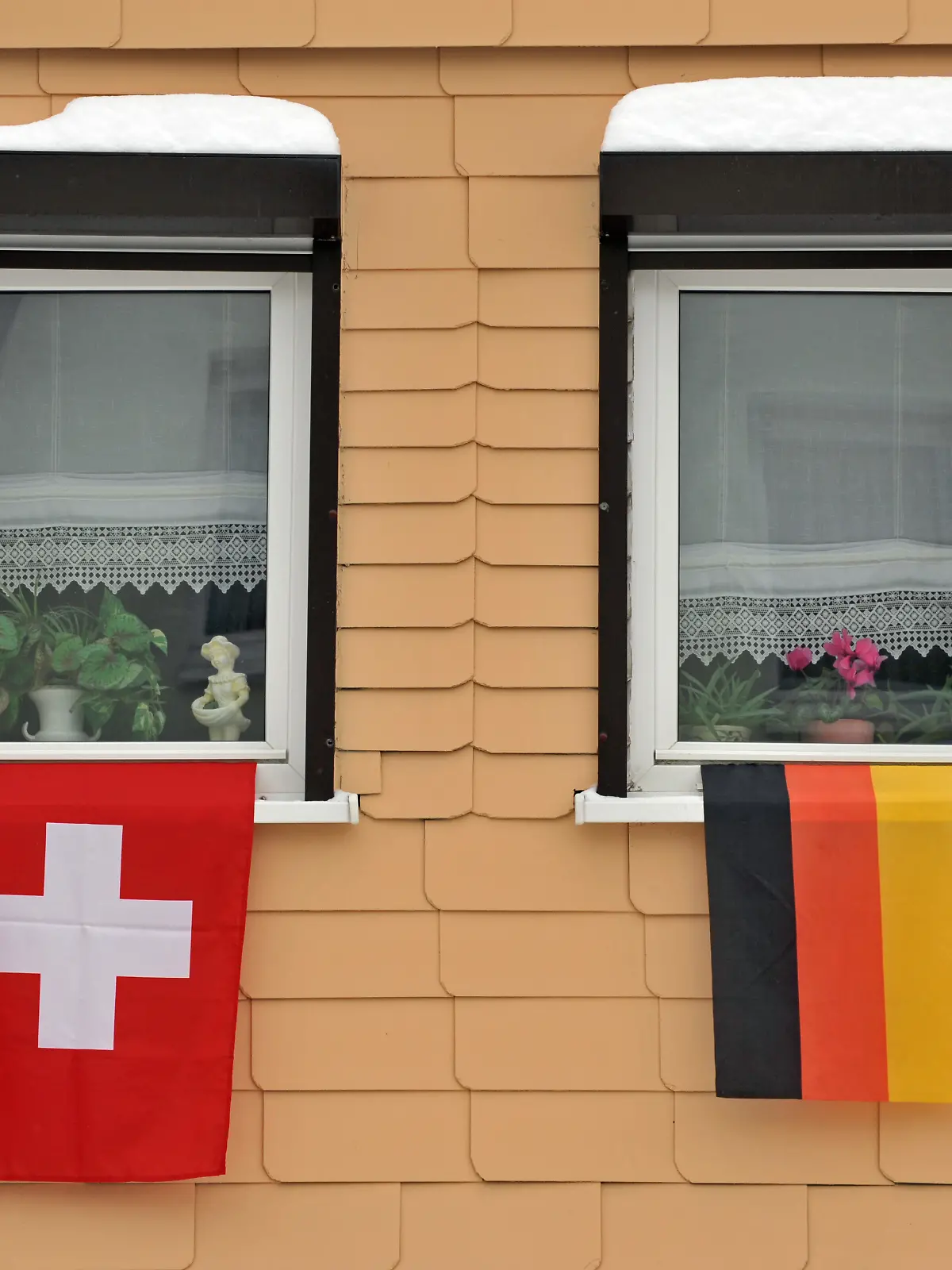 Eine deutsche und eine Schweizer Flagge hängen am Dienstag (02.02.2010) in Klingenthal (Sachsen) am Fenster eines Hauses. Für den Skisprung-Weltcup haben die Einwohner des Ortes die Häuser geschmückt. Der Kauf gestohlener Bankdaten über deutsche Steuersünder in der Schweiz ist nach Worten von Finanzminister Schäuble (CDU) beschlossene Sache. Bei Schweizer Großbanken wächst in der Steueraffäre die Nervosität. Foto: Martin Schutt dpa/lsn ++ +++ dpa-Bildfunk +++