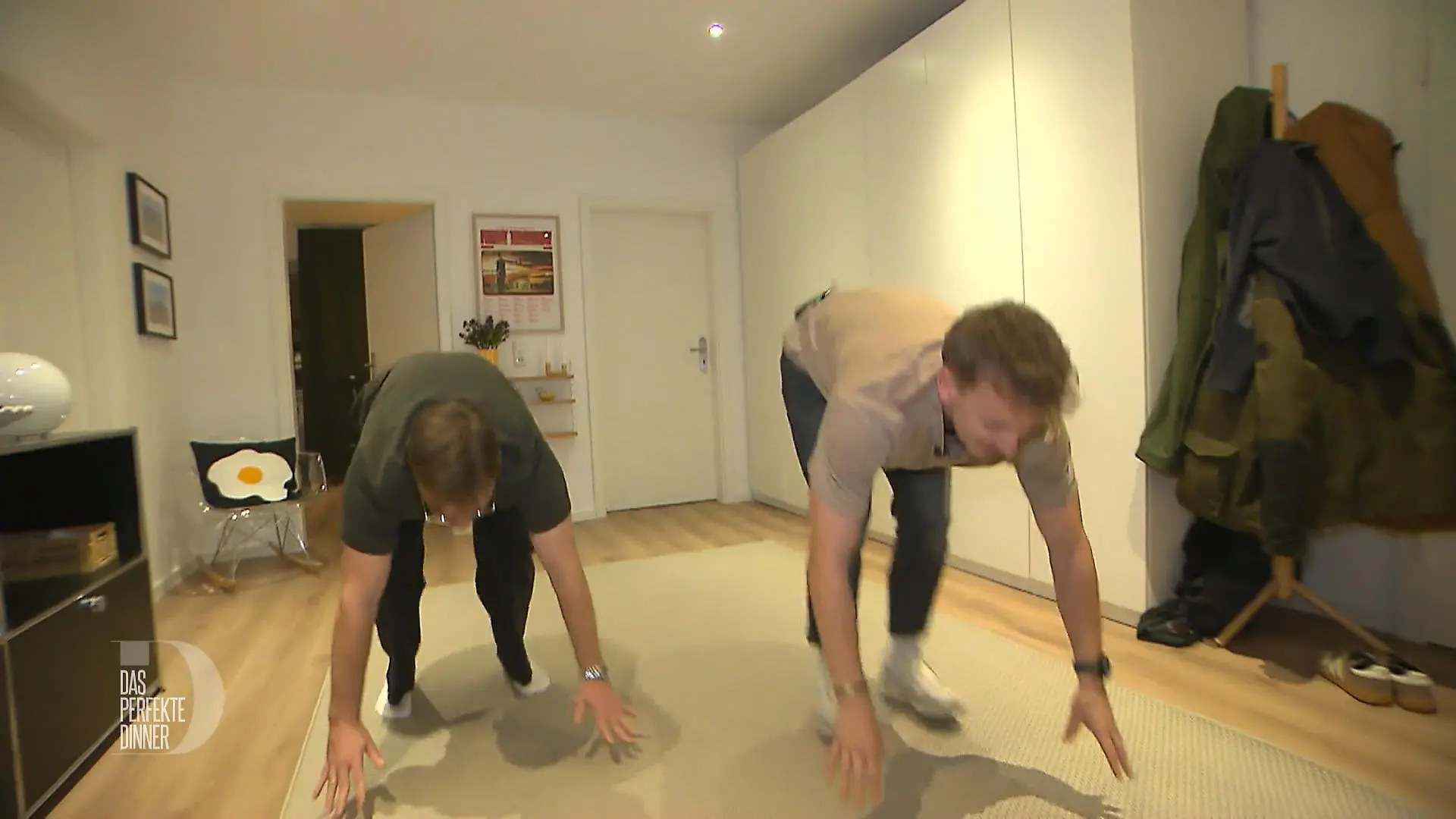 Das perfekte Dinner: Zwei junge Männer mit einer Sporteinlage auf einem Teppich im Flur
