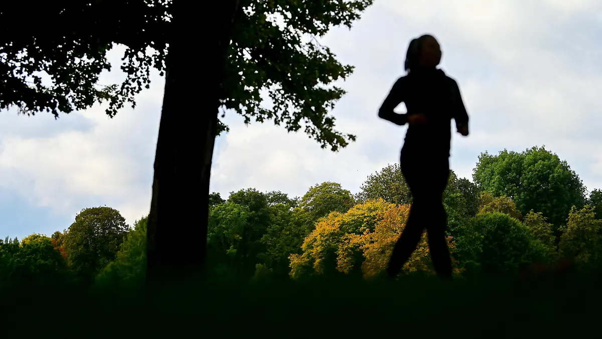 Eine Joggerin ist vor den herbstlich gefärbten Bäumen am Schlossteich in Chemnitz unterwegs. Die Woche klingt vielerorts mit wechselhaftem Herbstwetter aus.