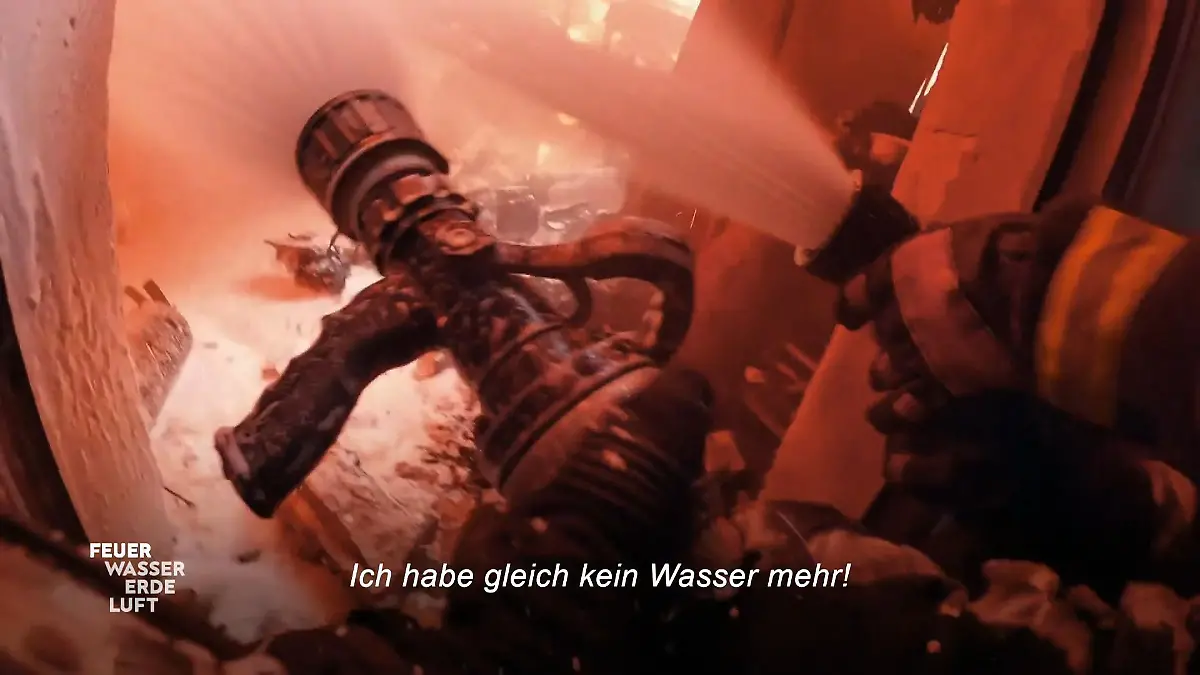 Feuer, Wasser, Erde, Luft - Retter in ihrem Element: Löschschlauch im Einsatz, darunter der Schriftzug „Ich habe gleich kein Wasser mehr!”