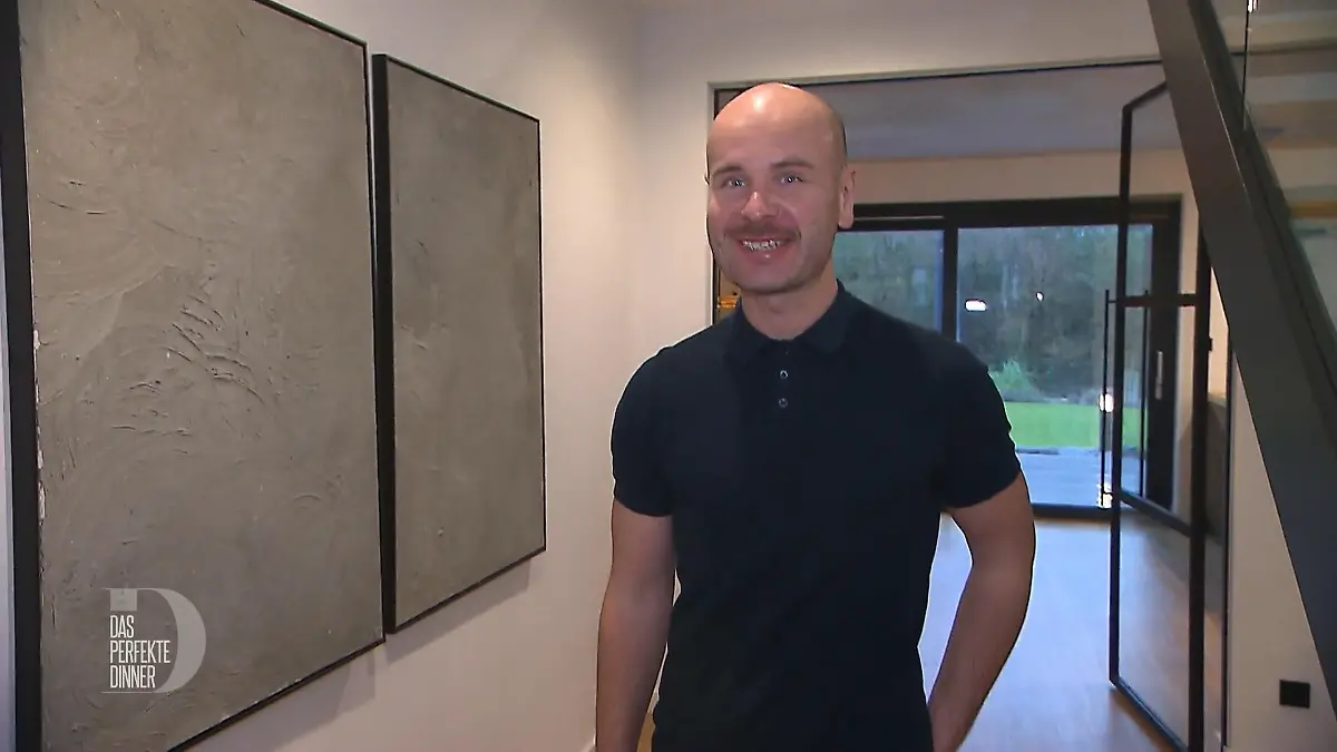 Das perfekte Dinner: Schlanker Mann mit Glatze und schwarzem Poloshirt im minimalistischen Flur seines Hauses