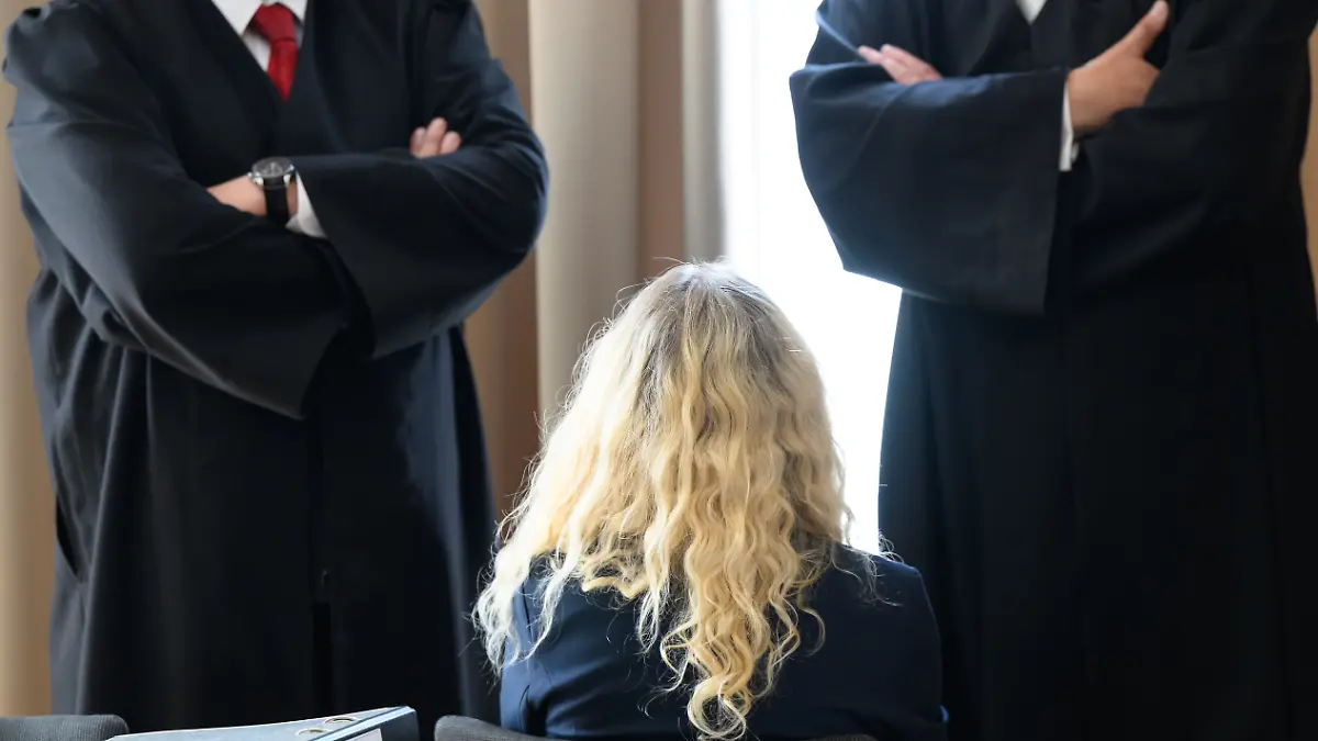 Die Hauptangeklagte (M) sitzt vor Beginn des Prozesses gegen eine 52 Jahre alte Frau und einen 76 Jahre alten Mann wegen Mordes und Beihilfe in einem Verhandlungssaal im Landgericht, daneben stehen ihre Rechtsanwälte. Die Angeklagte soll ihren Ehemann im September vergangenen Jahres absichtlich angefahren haben. Der 76-Jährige wurde schwer verletzt und starb. Der Mitangeklagte soll den Plan der Frau, ihren Mann zu töten, gekannt und ihr das Auto dafür besorgt haben. Ihm wird Beihilfe vorgeworfen. +++ dpa-Bildfunk +++