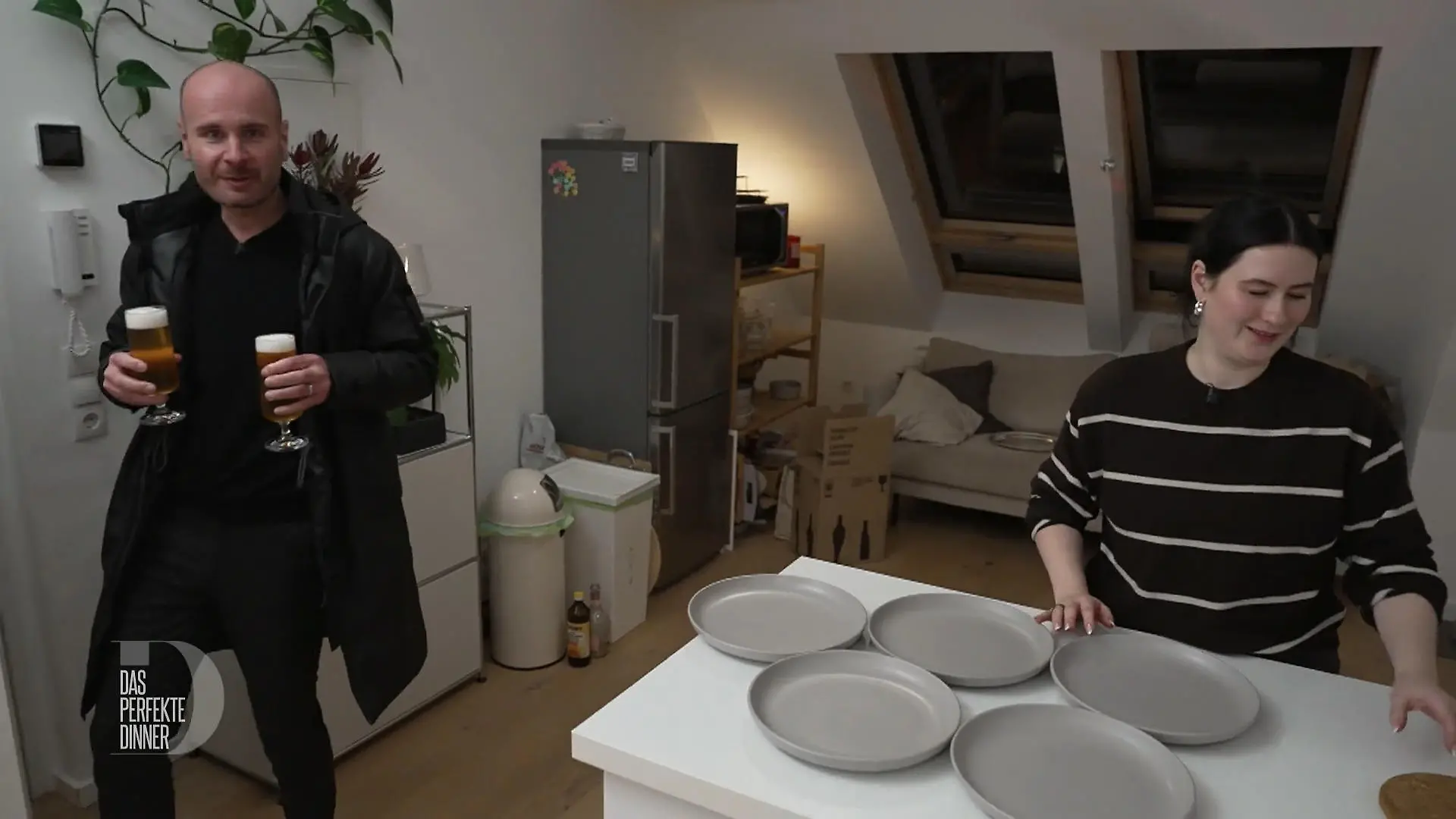 Das perfekte Dinner: Ein Gast steht in Jacke mit zwei frisch gezapften Gläsern Pils in der Hand an der Wohnungstür.