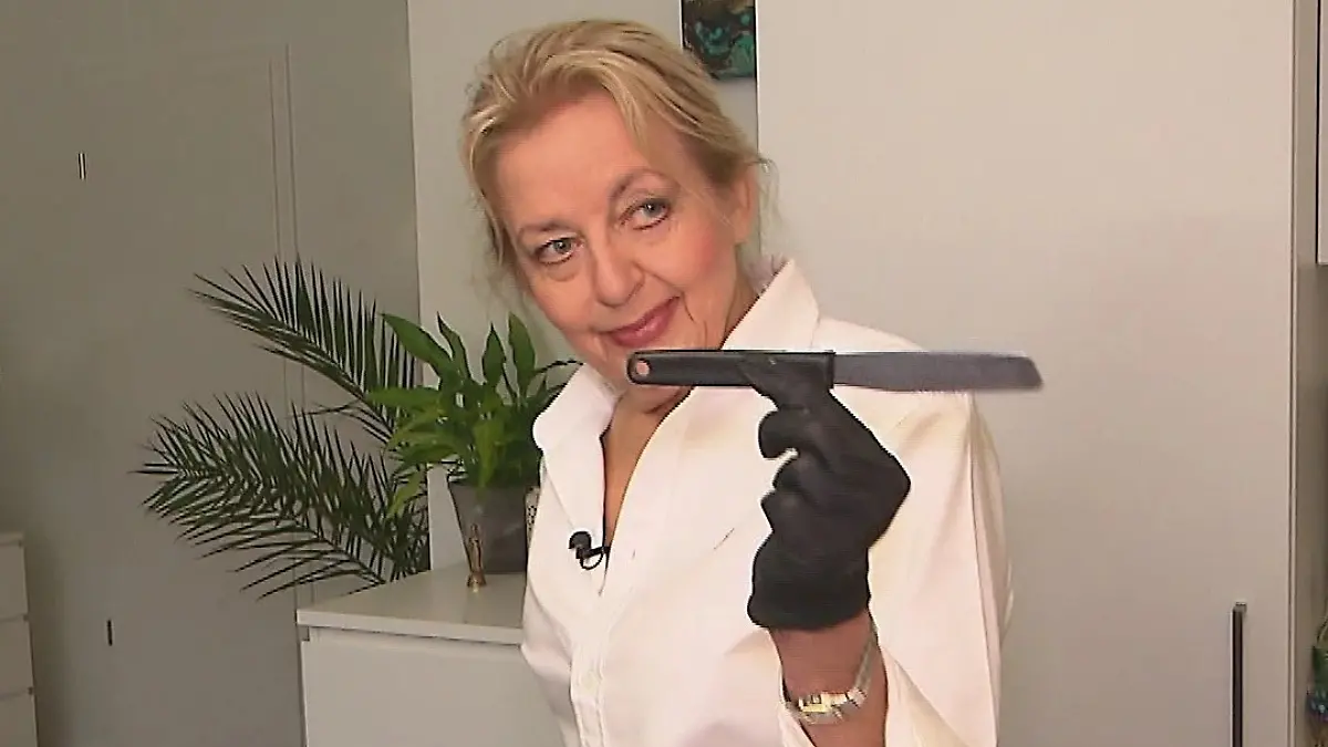 Das perfekte Dinner: Ältere blonde Frau schaut mit einem Messer in der Hand in die Kamera