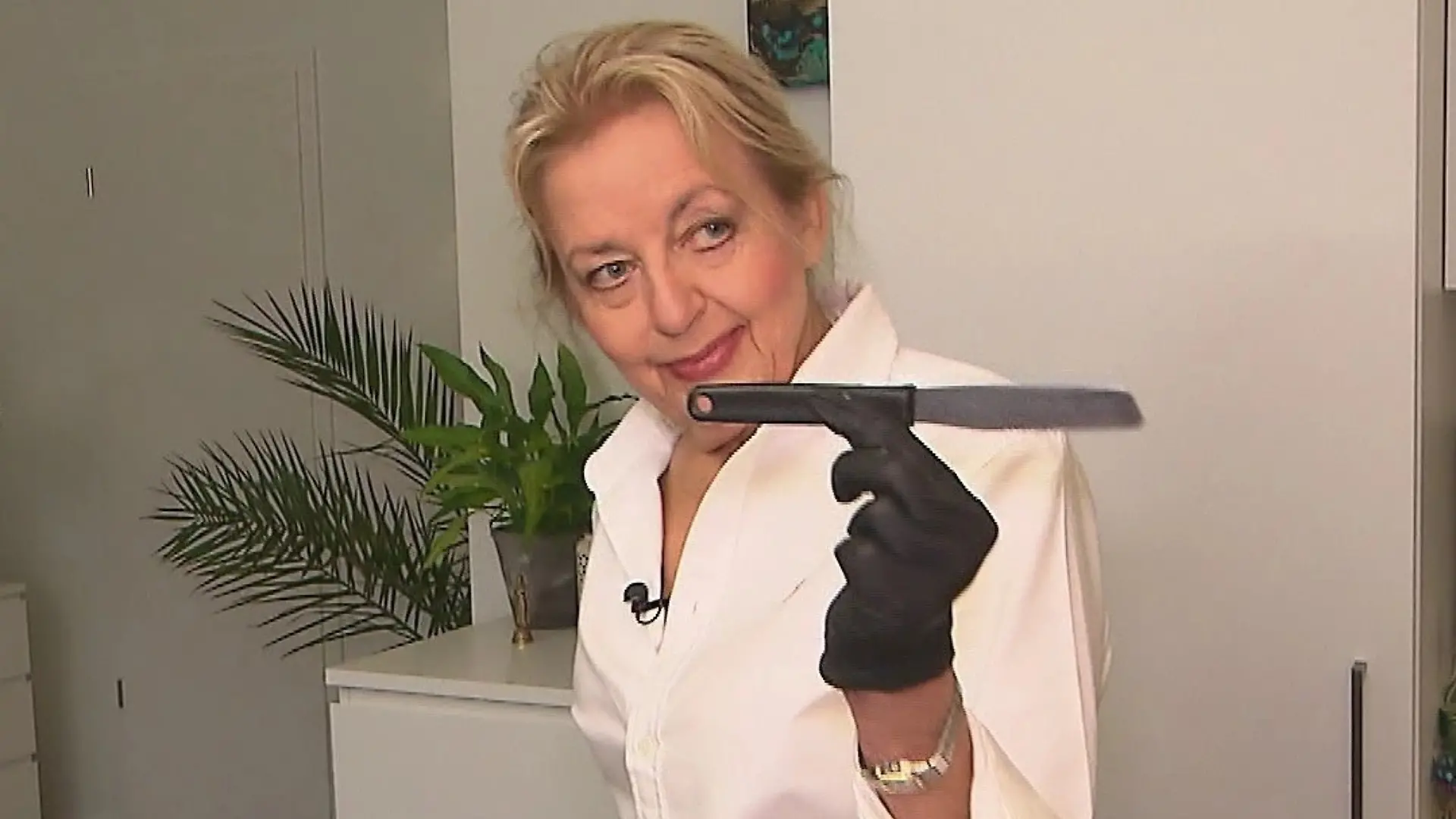 Das perfekte Dinner: Ältere blonde Frau schaut mit einem Messer in der Hand in die Kamera