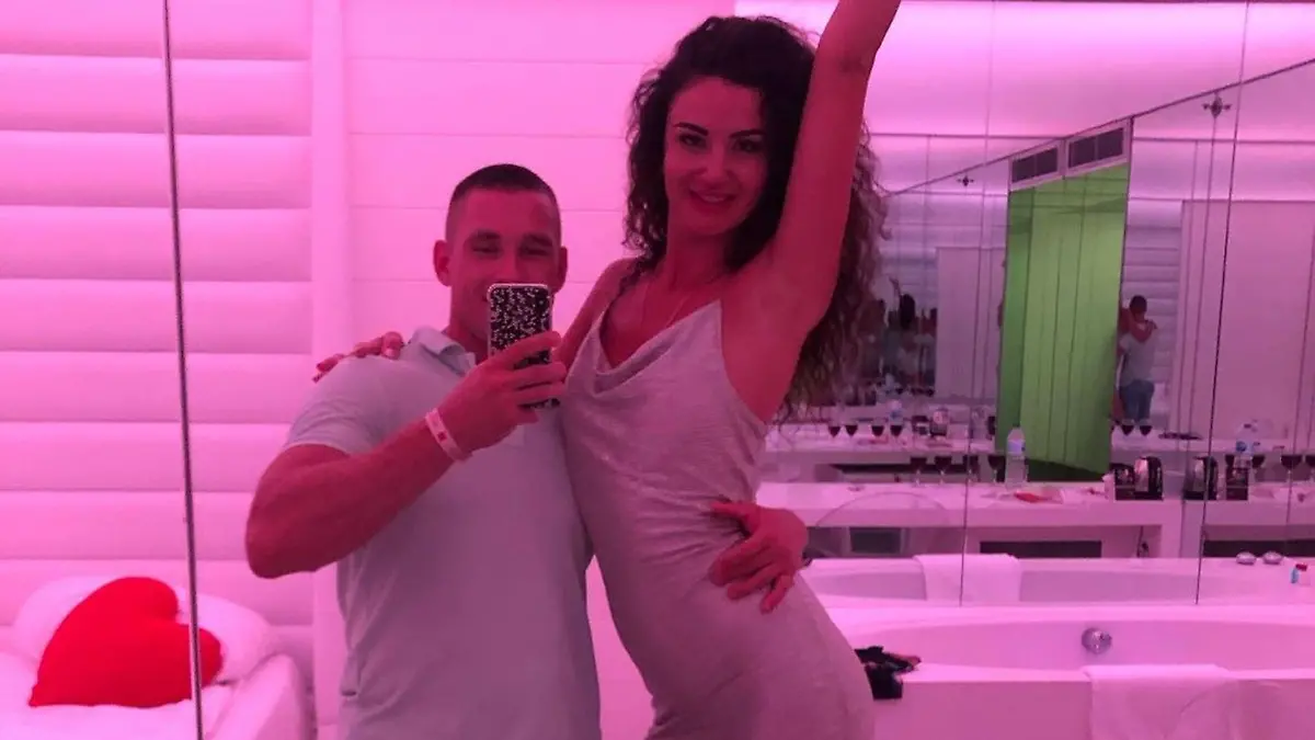 Anastasia posiert im Spiegel neben ihrem Mann.