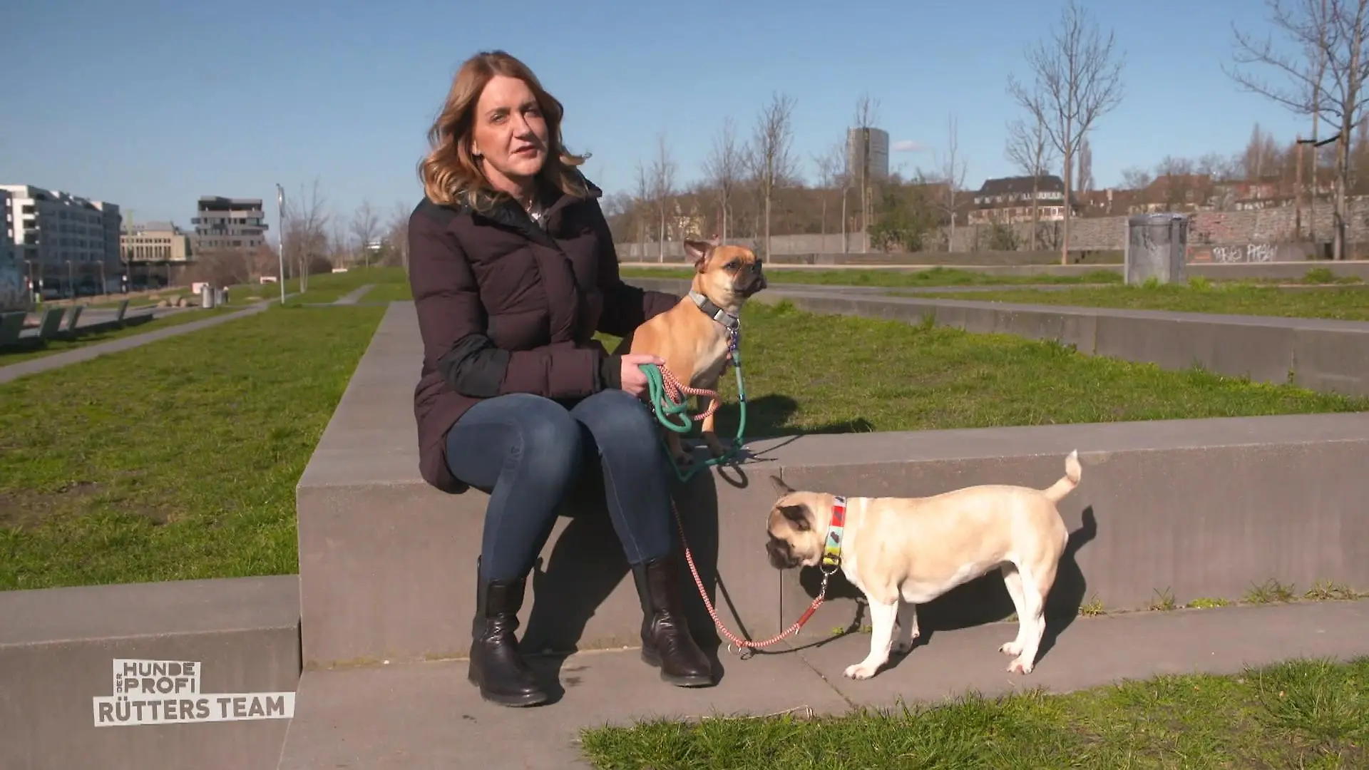 Der Hundeprofi - Rütters Team: Halterin Claudia sitzt auf einer Einfassung, an der Leine hat sie ihre beiden Hunde