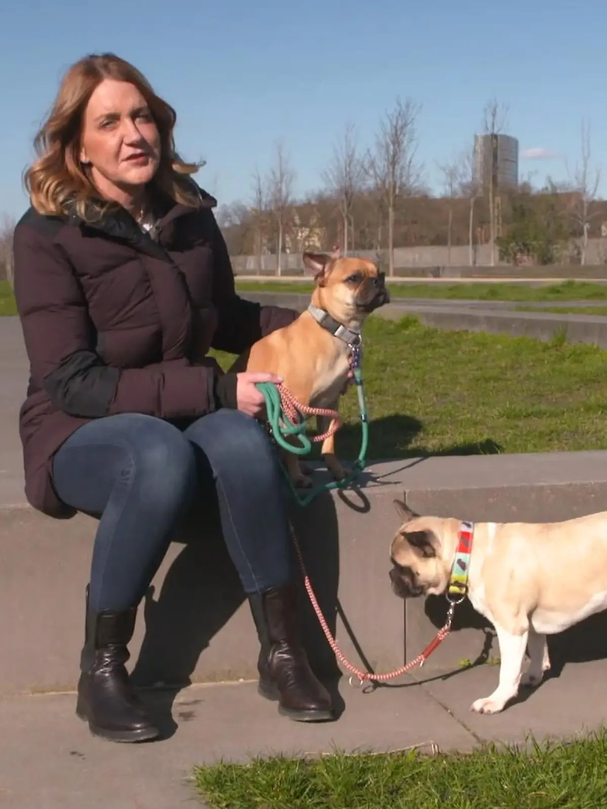 Der Hundeprofi - Rütters Team: Halterin Claudia sitzt auf einer Einfassung, an der Leine hat sie ihre beiden Hunde