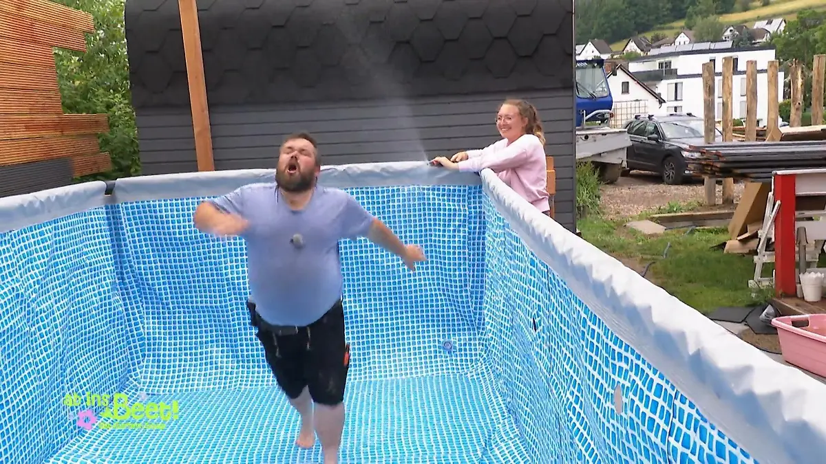 Ab ins Beet: Michel versucht, vor seiner mit Wasser spritzenden Frau im Pool wegzurennen