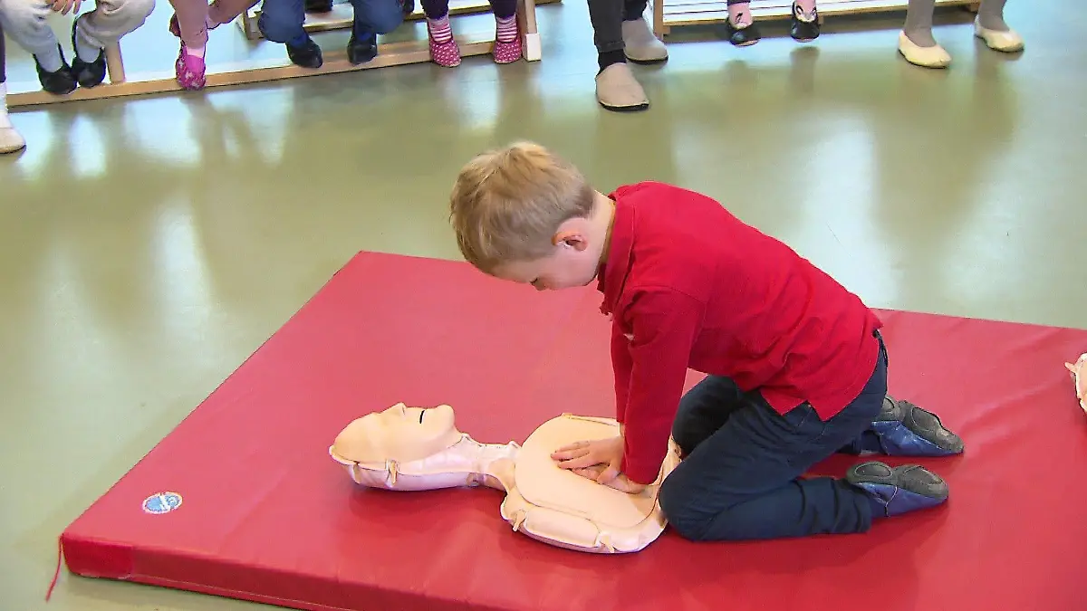 Kindergartenkind Paul drückt seine Hände auf eine Reanimationspuppe.
