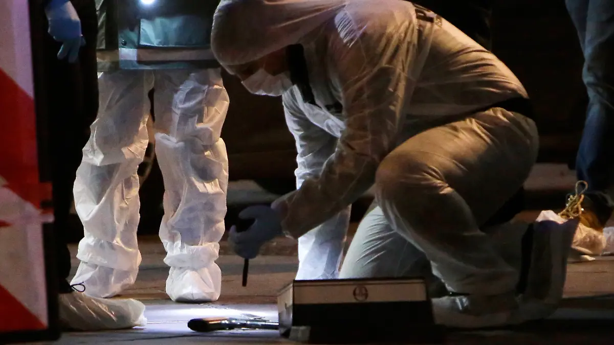 ARCHIV - 19.02.2019, Frankreich, Marseille: Ein Polizist untersucht eine Waffe, die auf dem Bürgersteig liegt, nach einem Vorfall. Im südfranzösischen Marseille startet am Montag (08.30 Uhr) ein Prozess um einen blutigen Drogenkrieg zwischen zwei konkurrierenden Banden in der Hafenstadt. (zu dpa: «Drogenkrieg in Marseille - Prozess gegen Clan-Chef startet») Foto: Claude Paris/AP/dpa +++ dpa-Bildfunk +++