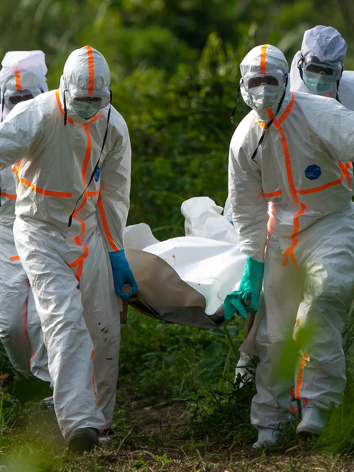 FILE - In this Sunday, July 14 fike, 2019 photo, burial workers dressed in protective gear carry the remains someone that died of Ebola, in Beni, Congo. The World Health Organization has issued an unusual statement raising questions about whether Tanzania is covering up possible cases of the deadly Ebola virus. It is a cause for concern during a regional outbreak recently declared a rare global health emergency.. (AP Photo/Jerome Delay)