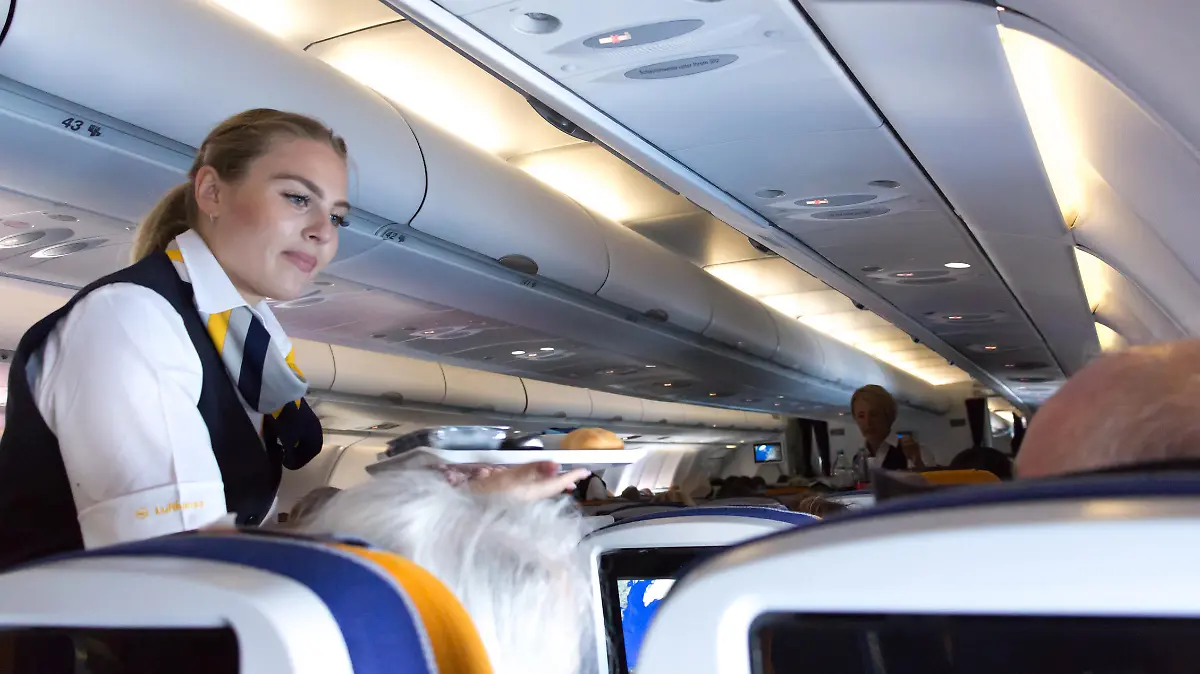 Munich: A female flight attendant is serving the lunch to a passenger sitting in the economy class of the route Munich - Vancouver of Lufthansa Airlines.