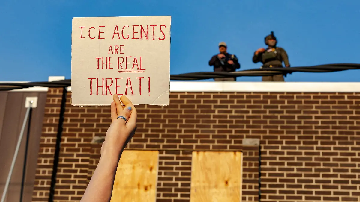 FILE PHOTO: A protester holds up a sign as federal agents stand guard on top of the Broadview ICE detention facility, after U.S. President Donald Trump ordered increased federal law enforcement presence to assist in crime prevention, in Broadview, Illinois, U.S. September 19, 2025. REUTERS/Jim Vondruska/File Photo
