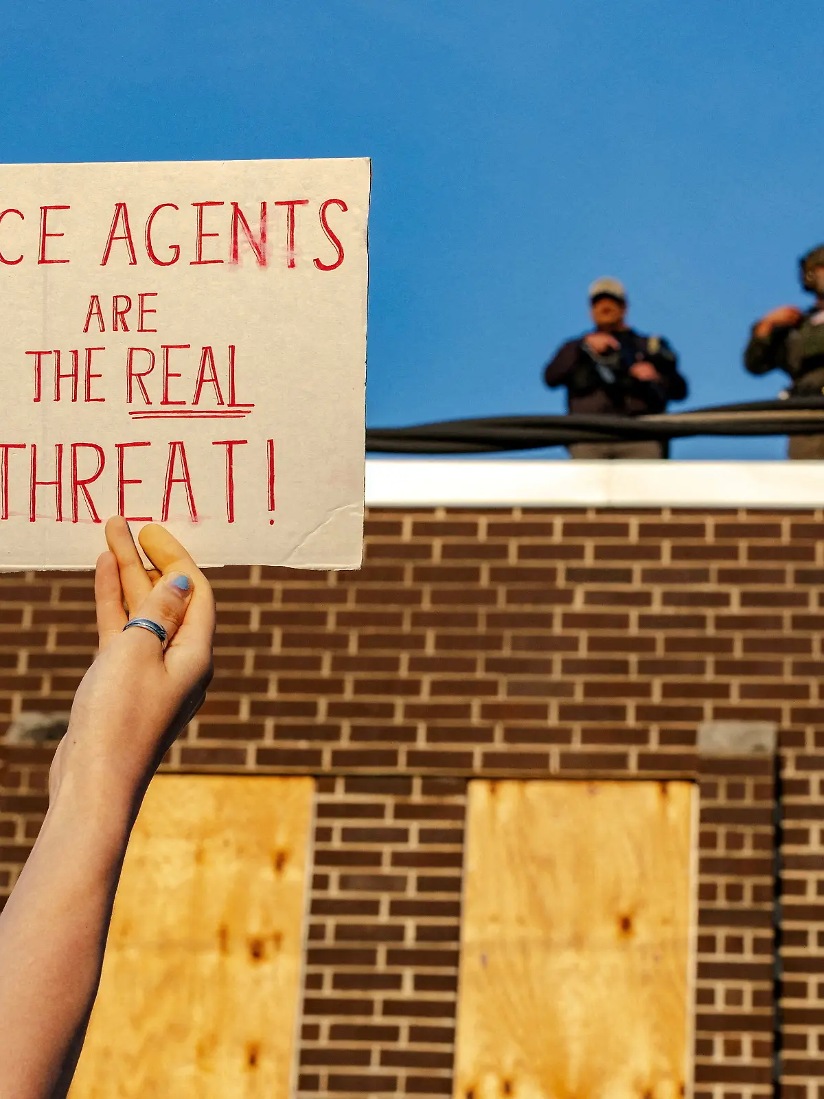 FILE PHOTO: A protester holds up a sign as federal agents stand guard on top of the Broadview ICE detention facility, after U.S. President Donald Trump ordered increased federal law enforcement presence to assist in crime prevention, in Broadview, Illinois, U.S. September 19, 2025. REUTERS/Jim Vondruska/File Photo