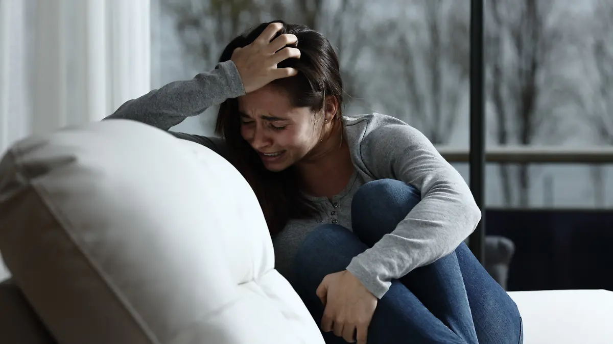 Frau liegt weinend auf dem Sofa