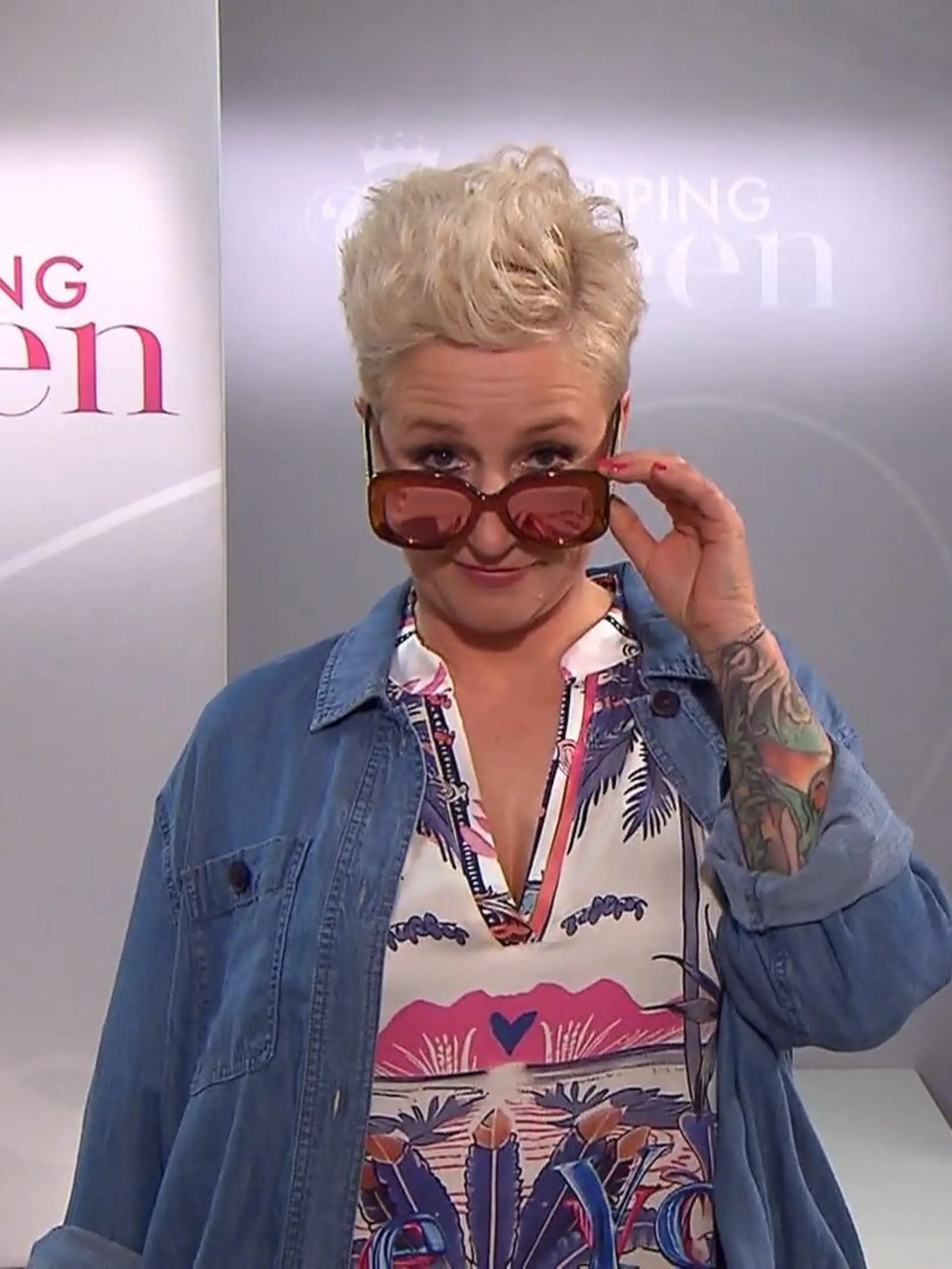 Sabine auf dem Laufsteg, blickt in die Kamera und zieht ihre Sonnenbrille leicht herunter. 