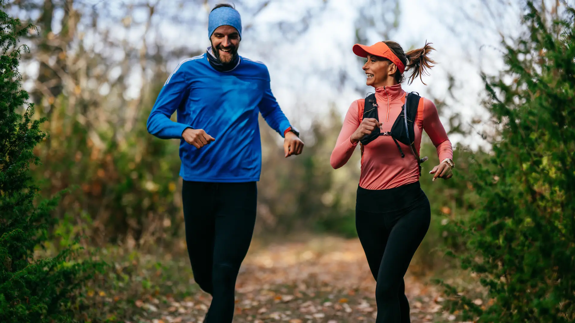 iling man and woman run together along a scenic forest trail on a cool day, dressed in athletic gear, enjoying nature, fitness, and each others company. || Modellfreigabe vorhanden