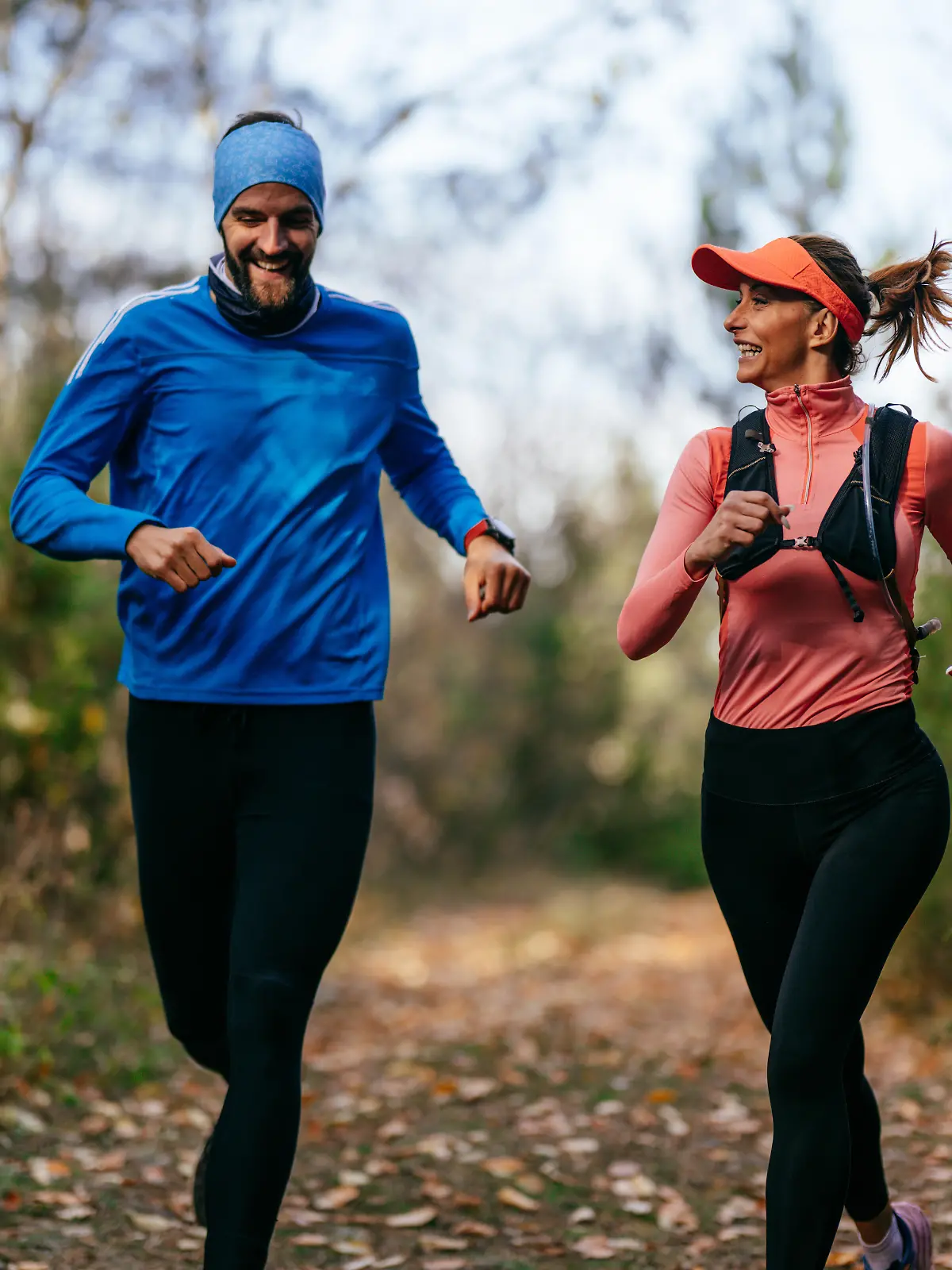 iling man and woman run together along a scenic forest trail on a cool day, dressed in athletic gear, enjoying nature, fitness, and each others company. || Modellfreigabe vorhanden