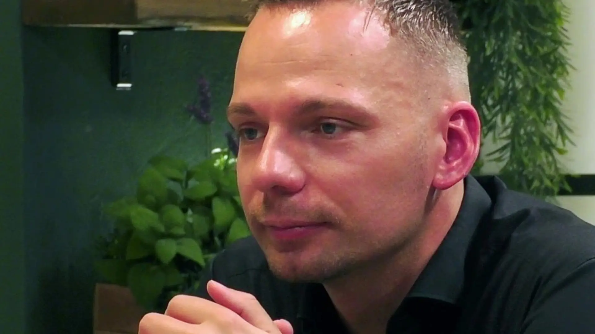 Tobi sitzt am Tisch mit aufgestützten Ellenbogen.