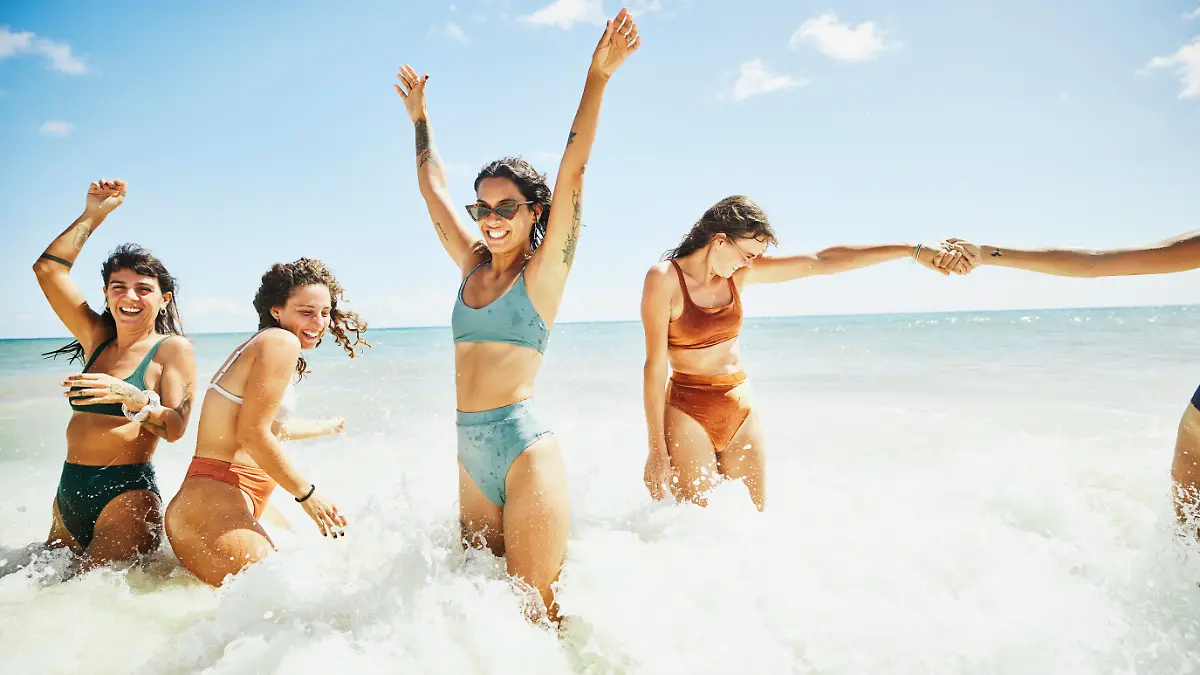Eine Gruppe von Frauen in Bikinis geht im Meer baden.