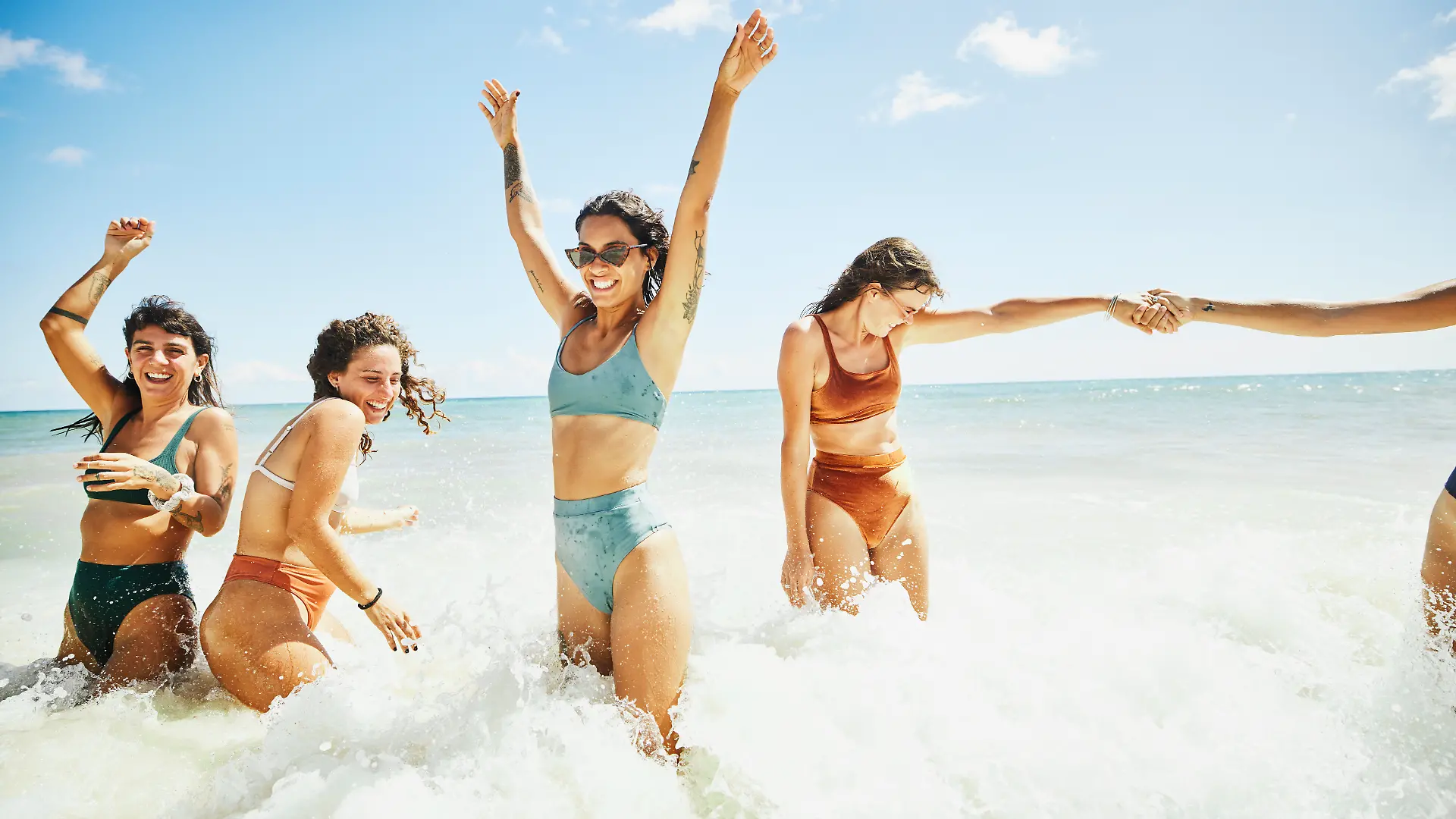 Eine Gruppe von Frauen in Bikinis geht im Meer baden.