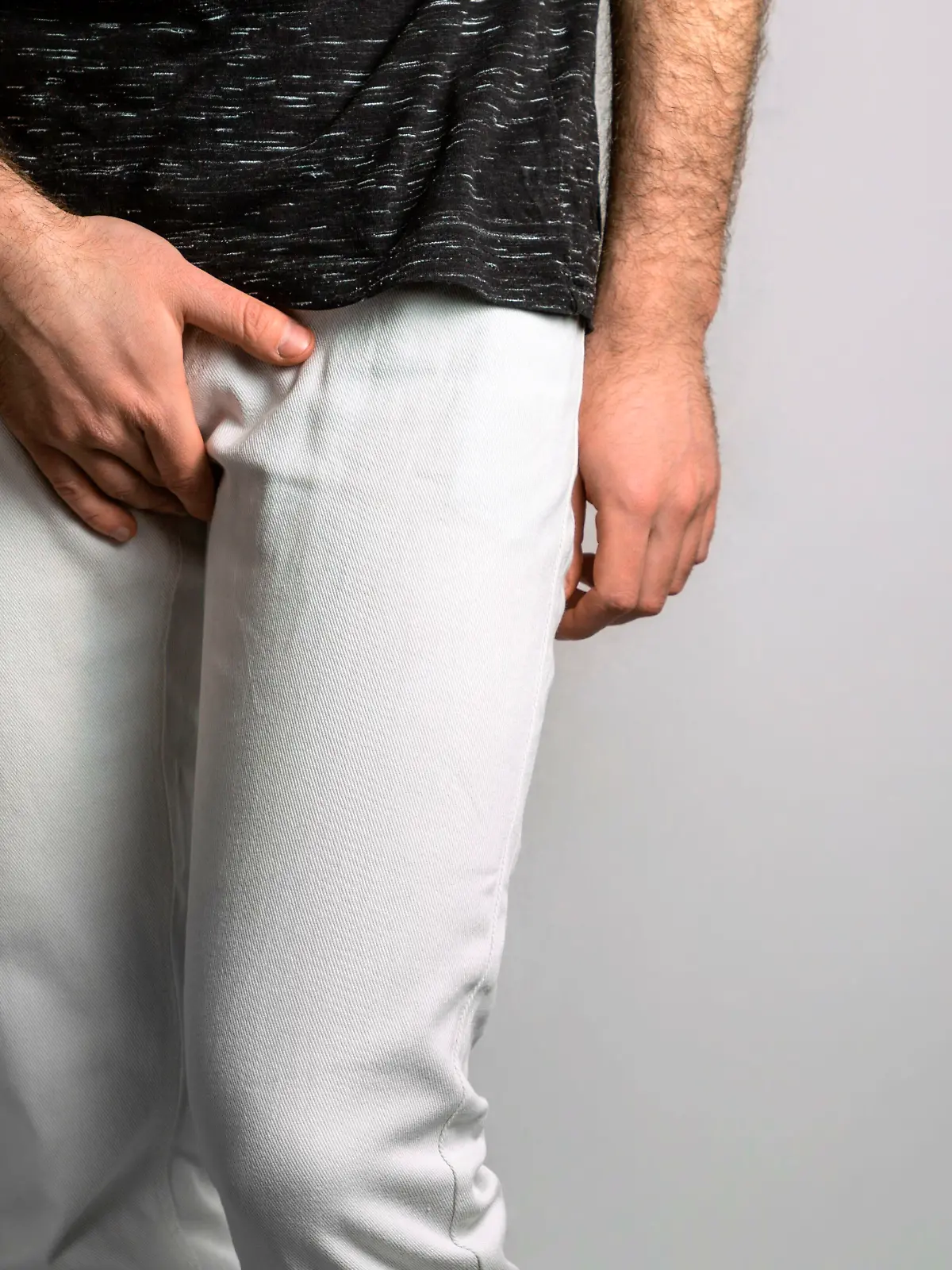 A man in white jeans holds his genitals with his hand. Disease for men. The concept of protection against sexually transmitted infections. Testicular