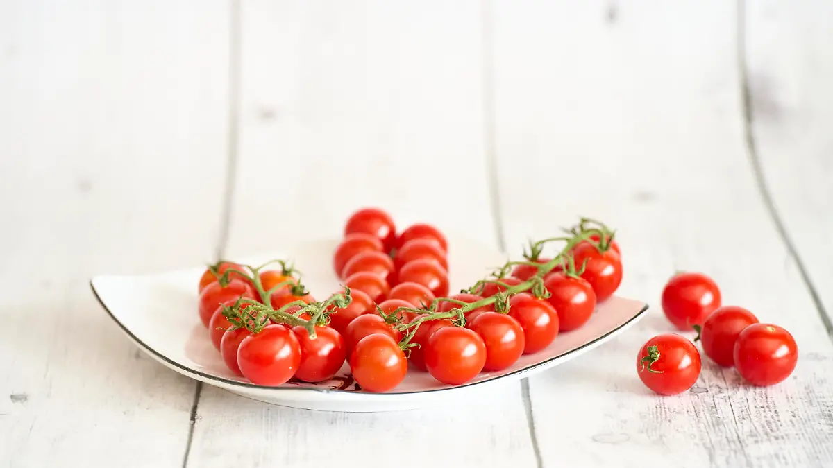 Rote Cherrytomaten auf weissem Teller und weissem Holztisch. Fehraltorf, Schweiz