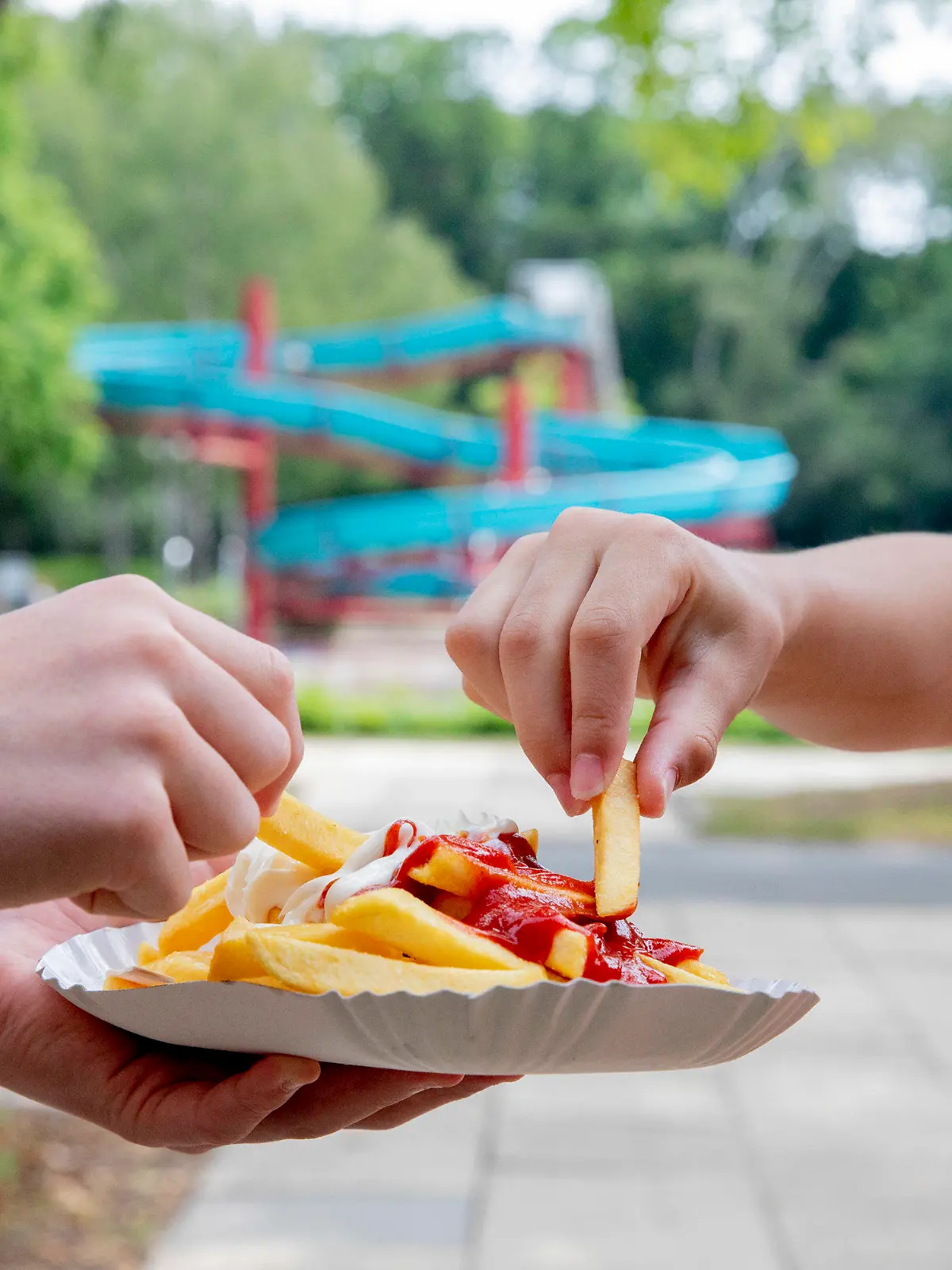 18.06.2020, Berlin: Kinder essen im Sommerbad Humboldthain Pommes mit Ketchup und Mayo vom Imbiss «Tropez». (zu dpa "Pommes: Warum kriegt man im Freibad Heißhunger drauf?") Foto: Christoph Soeder/dpa +++ dpa-Bildfunk +++