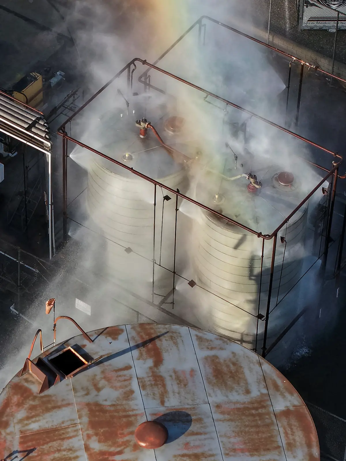 A drone picture shows water being sprayed on a tank as a chemical incident involving a failing tank of flammable liquid called methyl methacrylate, used in the aerospace industry, has forced an evacuation in the surrounding area in Garden Grove, California, U.S. May, 22, 2026. REUTERS/ Caroline Brehman