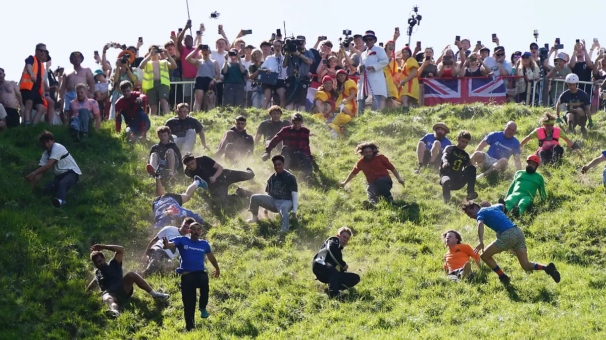 Zahlreiche Männer stürzen sich einen Hügel hinunter - auf der Jagd nach einem rollenden Käselaib. Das traditionelle wie kuriose Käserennen wird jährlich in dem Ort in der Grafschaft Gloucestershire veranstaltet. +++ dpa-Bildfunk +++