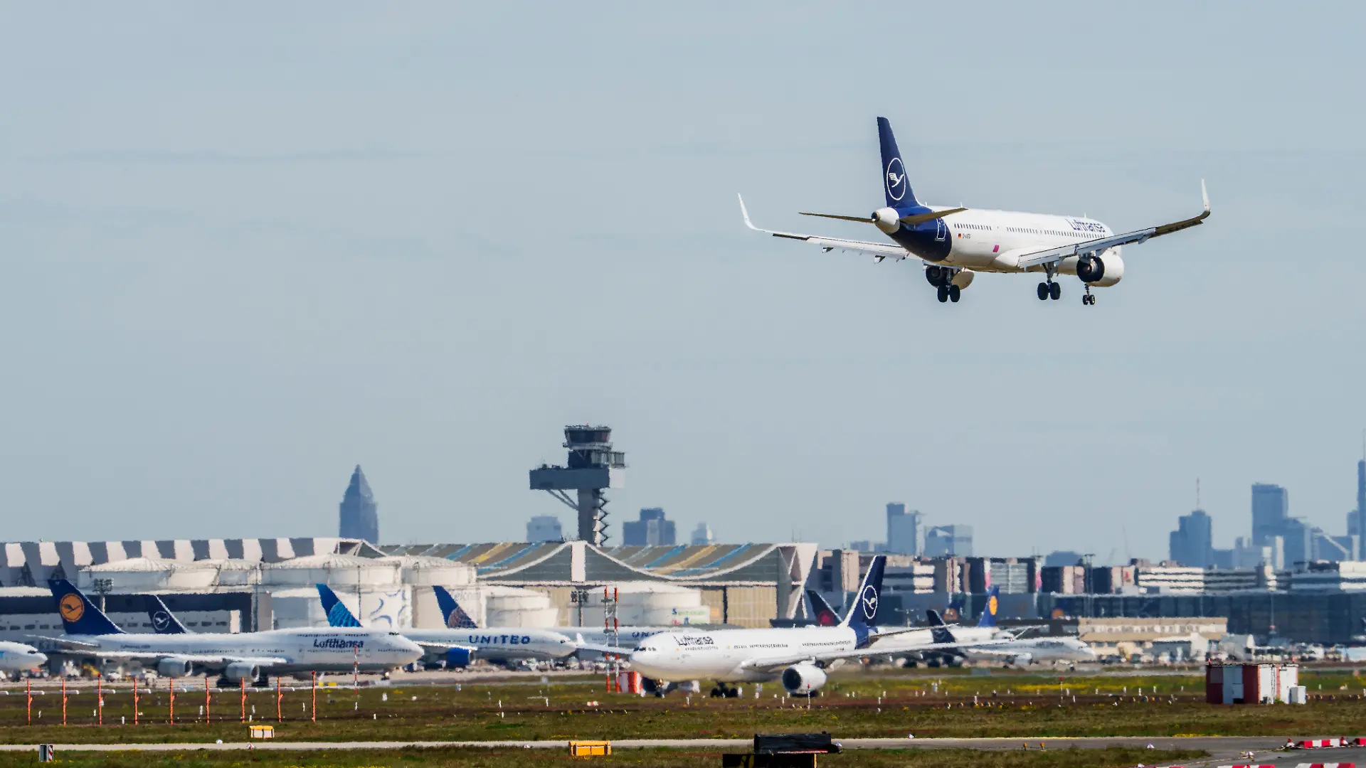 Eine Maschine der Lufthansa ist im Landeanflug auf den Flughafen Frankfurt. Im Hintergrund sind die Kerosinlager und Maschinen auf ihrer Parkposition zu sehen. Mehrere Airlines bereiteten sich nach Medienberichten auf einen möglichen Kersosinmangel in Folge des Iran-Krieges vor.