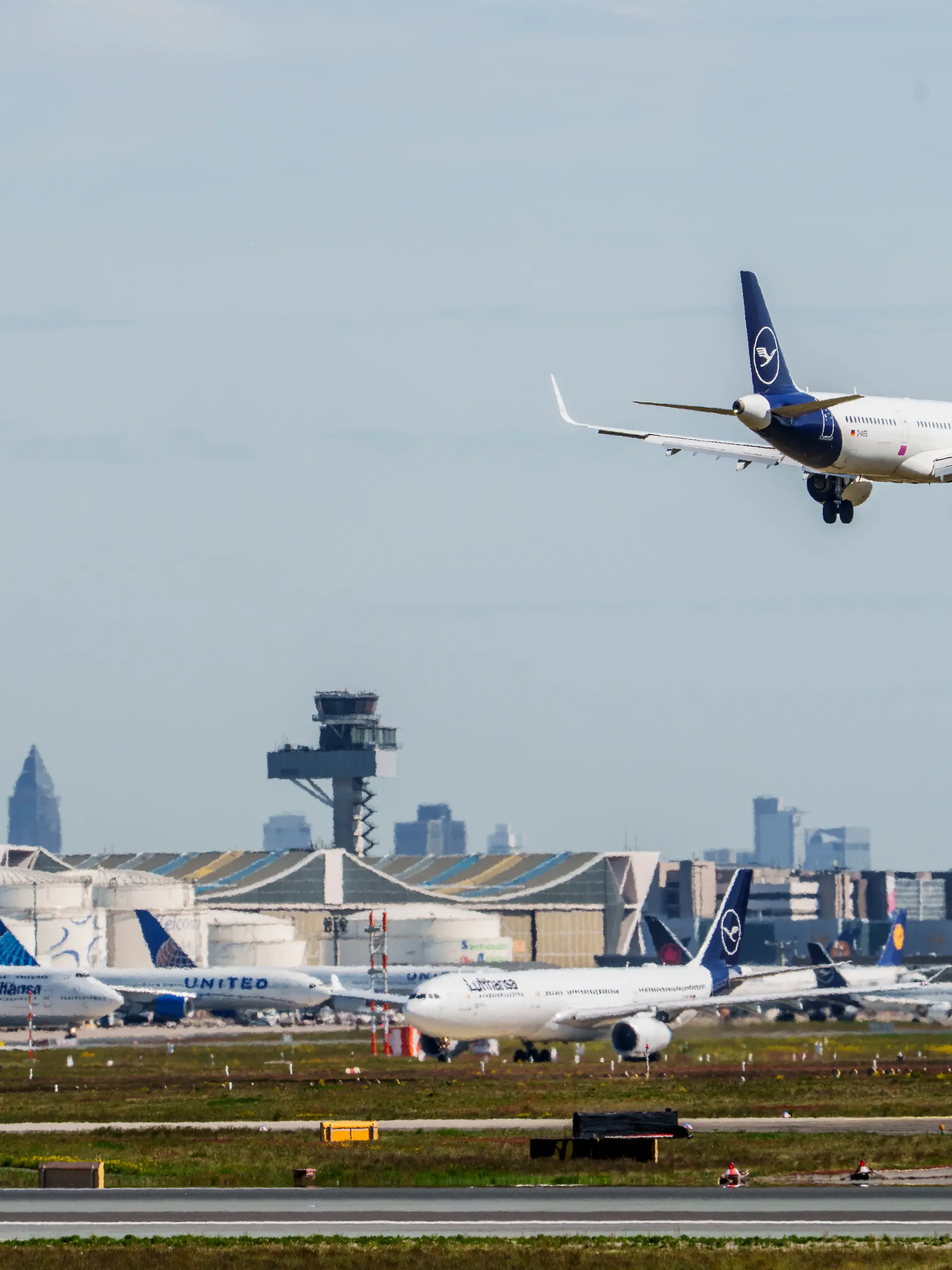 Eine Maschine der Lufthansa ist im Landeanflug auf den Flughafen Frankfurt. Im Hintergrund sind die Kerosinlager und Maschinen auf ihrer Parkposition zu sehen. Mehrere Airlines bereiteten sich nach Medienberichten auf einen möglichen Kersosinmangel in Folge des Iran-Krieges vor.
