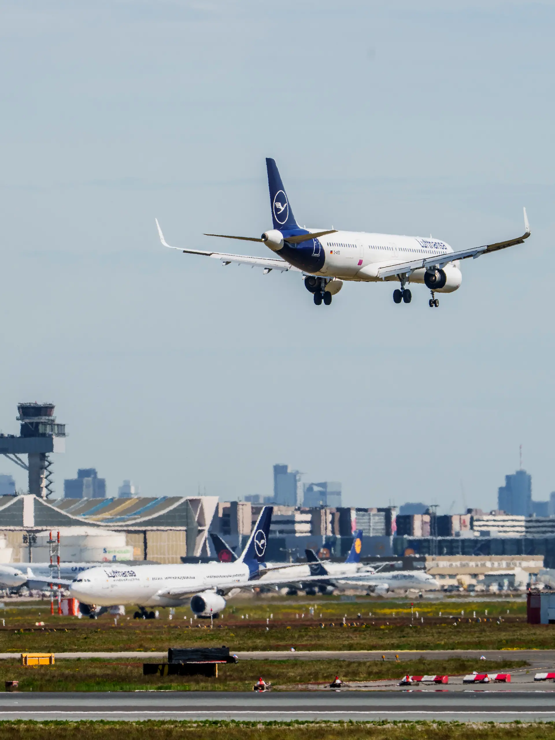 Eine Maschine der Lufthansa ist im Landeanflug auf den Flughafen Frankfurt. Im Hintergrund sind die Kerosinlager und Maschinen auf ihrer Parkposition zu sehen. Mehrere Airlines bereiteten sich nach Medienberichten auf einen möglichen Kersosinmangel in Folge des Iran-Krieges vor.