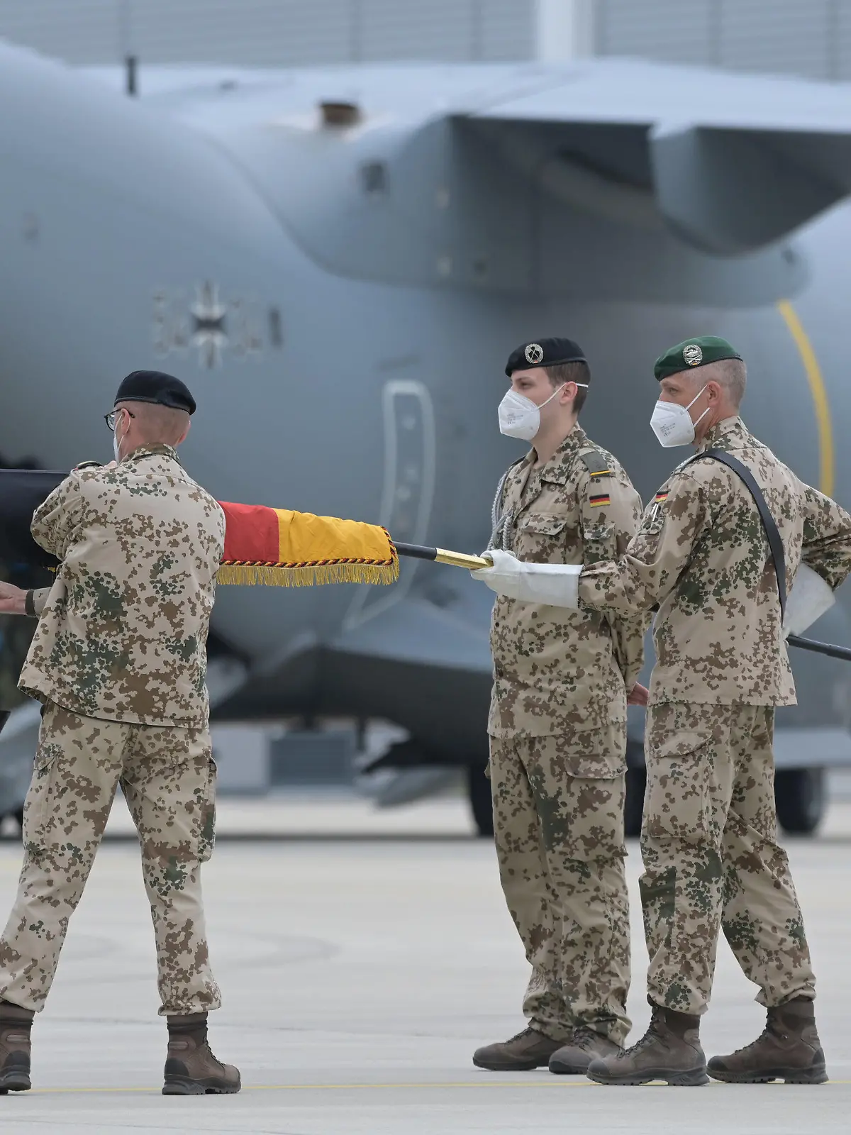 30.06.2021, Niedersachsen, Wunstorf: Brigadegeneral Ansgar Meyer (l), der letzte Befehlshaber der Bundeswehr in Afghanistan, rollt vor dem Transportflugzeug vom Typ Airbus A400M der Luftwaffe die Truppenfahne ein. Die letzten Soldaten des deutschen Afghanistan-Einsatzes sind auf dem niedersächsischen Fliegerhorst ankommen. Am Vorabend war der Einsatz nach fast 20 Jahren beendet worden. Die Soldaten waren mit vier Militärmaschinen aus dem Feldlager in Masar-i-Scharif im Norden von Afghanistan ausgeflogen worden. Foto: Hauke-Christian Dittrich/dpa-Pool/dpa +++ dpa-Bildfunk +++