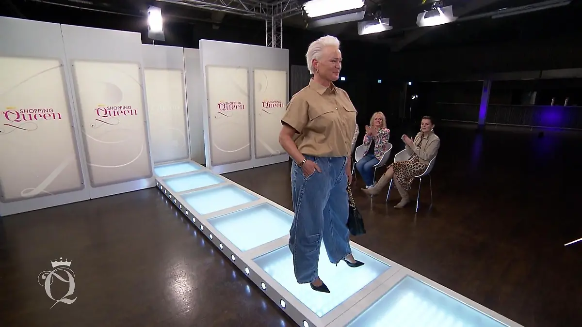 Doreen posiert auf dem Laufsteg, eine Hand in der Hosentasche.