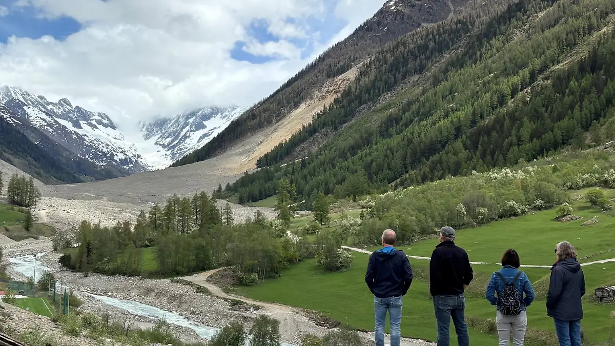 PRODUKTION - 05.05.2026, Schweiz, Blatten: Besucher schauen an der abgesperrten Straße auf den Schuttberg, wo einst das Dorf Blatten mit 300 Einwohnern lag. Von dem Dorf ist nur wenig übrig geblieben, zunächst unversehrte Häuser sind im See versunken, der durch die gestaute Lonza hinter dem Schuttberg entstand. (zu dpa: «Engel und Roboter: Was nach dem Bergsturz bleibt») Foto: Christiane Oelrich/dpa +++ dpa-Bildfunk +++