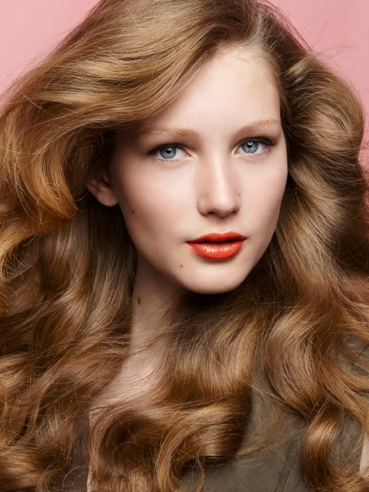 Ein Beauty-Foto einer Brünetten mit professioneller Frisur und Make-up vor einem dunklen Hintergrund